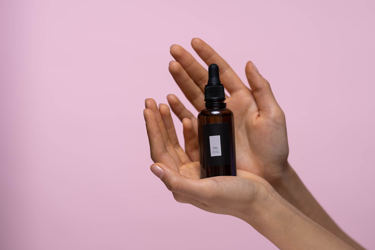 Person Holding A Brown Glass Bottle Of Serum